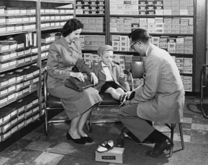 Side profile of a sales clerk helping a boy try on shoes in a shoe store Canvas Art