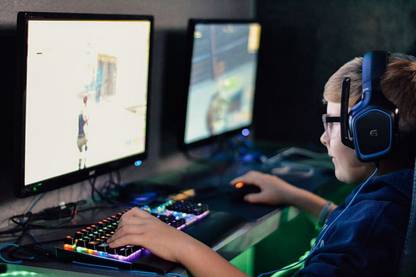 boy wearing headset playing computer game Paper Print