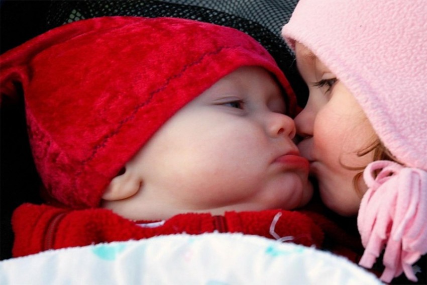 Young mother kissing her cute baby in funny red hat. | CanStock