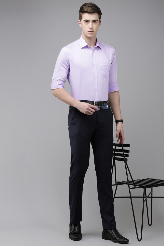 Dressing in a purple shirt gray pants a black tie a book nearby a young  handsome